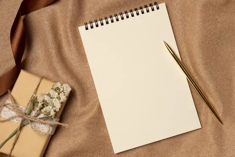 Empty notebook with pen and gift box on a fabric background from above. Cop.. Stock Photos