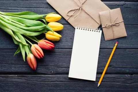Empty notebook, pencil and yellow and red tulips flowers on vintage wooden .. Stock Photos