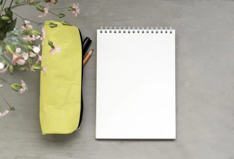 An empty notebook, a pencil case, and flowers on a gray background. Template Stock Photos