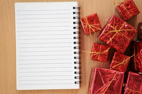 Empty notebook placed near the red gift box on a brown wooden floor. Foto stock