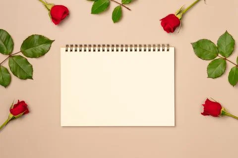 Empty notebook with red roses frame of on beige background. Flat lay, top v.. Stock Photos