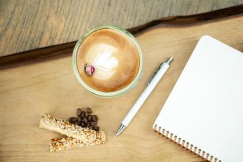 Empty notebook, white pen and cappuccino coffee on wooden table, top view Stock Photos