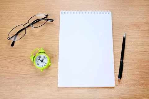 Empty notepad with alarm clock, pen and eyeglasses on table Foto stock
