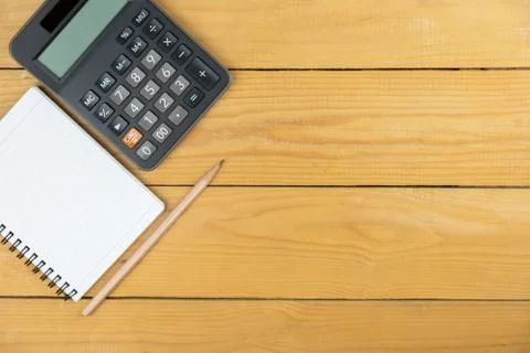 Empty notepad and calculator and pencil on wooden desk, copy space, top view  Stock Photos