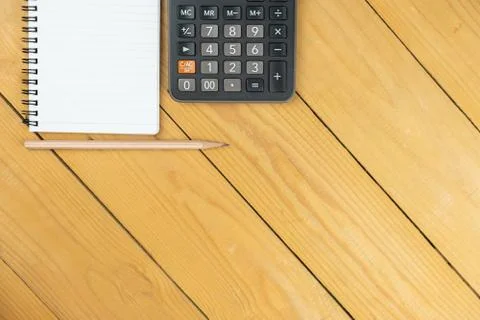 Empty notepad and calculator and pencil on wooden desk, copy space, top view  Stock Photos