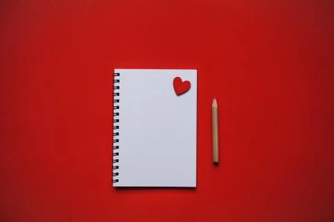 Empty notepad with heart on a red background. Near the pencil. Stock Photos