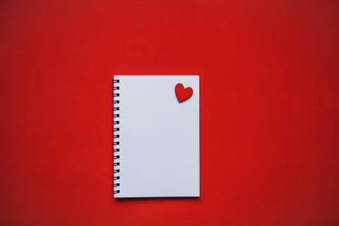Empty notepad with heart on a red background. Stock Photos
