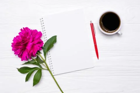 Empty notepad with place for text, pen, cup of coffee and peony flower on white Stock Photos
