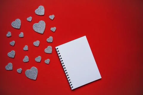 Empty notepad on red background. Near many hearts. Stock Photos