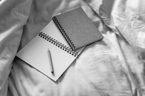 Empty notepads with copyspace and pencil on messy bed sheets Stock Photos