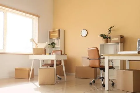 Empty office space with moving boxes and furniture, business relocation and n Stock Photos