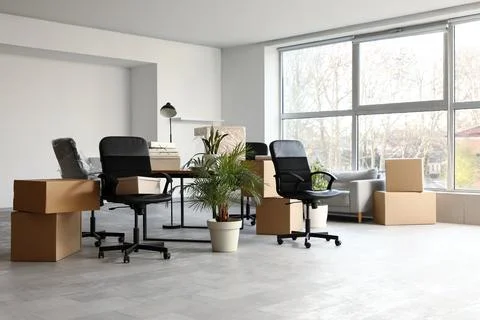 Empty office space with moving boxes and office chairs, business relocation a Stock Photos