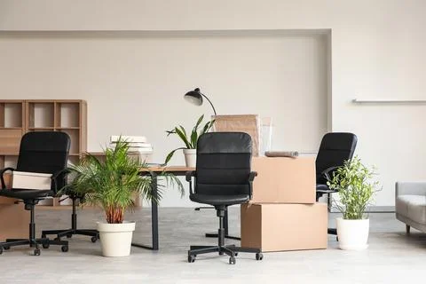Empty office space with moving boxes and office chairs, business relocation a Stock Photos