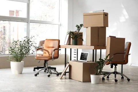 Empty office space with moving boxes and potted plants, business relocation a Stock Photos