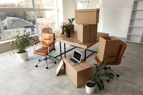 Empty office space with moving boxes, laptop, and plants, ready for business  Stock Photos