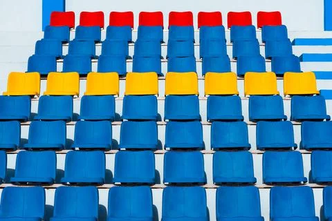Empty old blue seats in the blue,yellow and red in stadium. Stock Photos