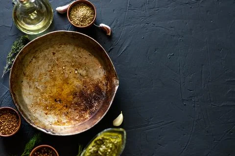 Empty old frying pan surrounded by spices on a dark background. Place for tex Stock Photos