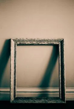 An empty, old picture frame standing next to a white wall. The closure of an  Stock Photos