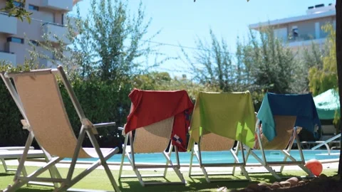 Empty open beach lounge chairs near the swimming pool in the backyard of hotel Stock Footage 162664638