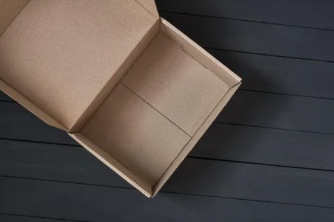 Empty open cardboard box on black wooden background. Delivery concept. Top vi Foto stock