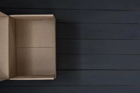 Empty open cardboard box on black wooden background. Delivery concept. Top vi 스톡 사진
