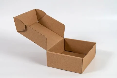 Empty open cardboard box standing on a light table. Stock Photos