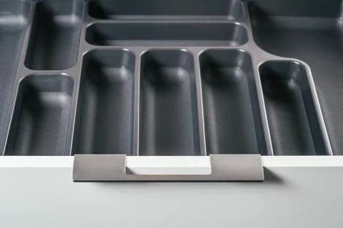 Empty open drawer of white kitchen set with black cutlery organizer tray. Sto Stock Photos