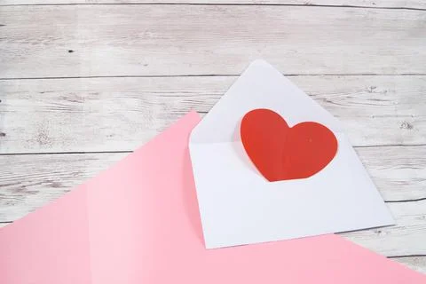 An empty open envelope with a red heart on a pink and wooden background, a co Stock Photos
