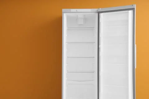 Empty open refrigerator against orange wall Stock Photos