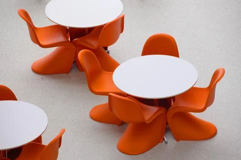 Empty orange chairs around round white tables, meeting Stock Photos