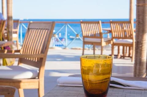 Empty orange glass on table at beach cafe Stock Photos