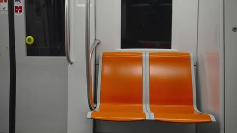 Empty orange seats inside public transit train remain still as tunnel lights Stock Footage 348100877