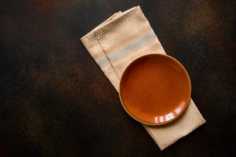 Empty orange spotted plate on dark background and napkin. Background for menu Stock Photos