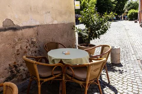 Empty Outdoor Bistro Table and Chairs on Historic Cobblestone Street Stock Photos