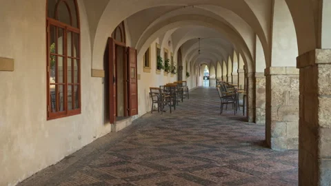 Empty outdoor cafe in historic vaulted gallery with stone arcade arches Stock Footage 341817568