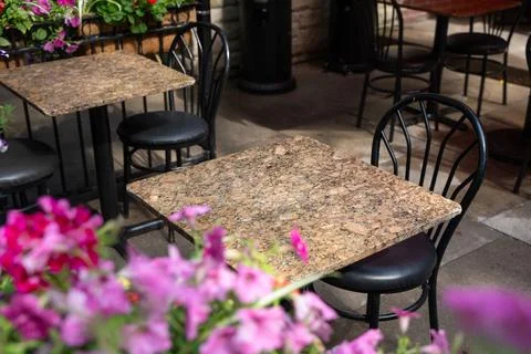 Empty outdoor cafe patio table beside pink flowers Stock Photos