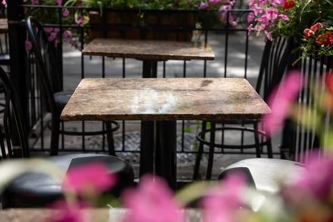 Empty outdoor cafe patio table beside pink flowers Stock Photos