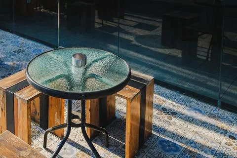Empty outdoor cafe table with glass top and ashtray in morning sunlight Foto stock