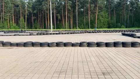 Empty outdoor go-kart track with tire barriers near pine forest Stock Footage 336796681