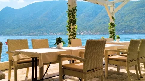 Empty outdoor restaurant table and chairs on sunny lakeside terrace Stock Footage 340533327