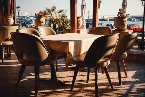 Empty outdoor restaurant table with comfortable chairs set on a sunny terra.. Stock Photos