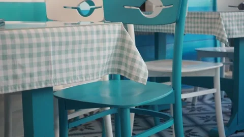 Empty outdoor restaurant terrace featuring blue wooden chairs and checkered.. Stock Footage 332578556