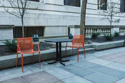 Empty outdoor seating area with two orange chairs and a round table near a .. Fotos Stock