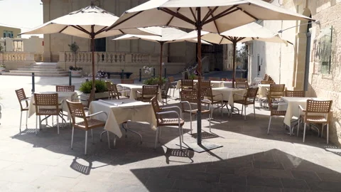 Empty outside restaurant seating with parasols,old stone plaza,Malta. Stock Footage 161689211