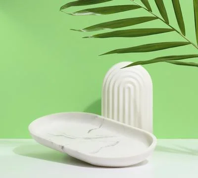 Empty oval white marble stand on a green background and a shadow from palm .. Stock Photos