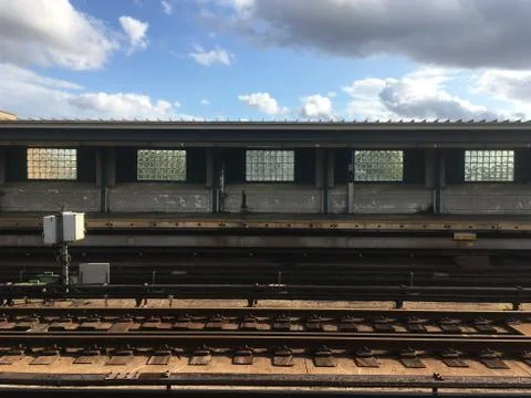 Empty overground subway platform with subway tracks in foreground. Blue sky a Stock Photos