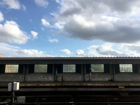Empty overground subway platform with subway tracks in foreground. Blue sky a Stock Photos