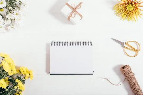 Empty page of open notepad among flat lay frame of flowers Fotos Stock