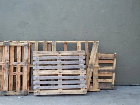 Empty pallets stacked against wall outside Stock Photos
