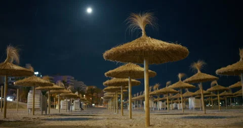 Empty Palma de Mallorca Beach at Night with Straw Sun Umbrellas and Moon Stock Footage 343595299